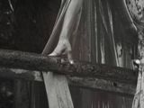 black and white photograph of a woman in a long dress standing on a bridge