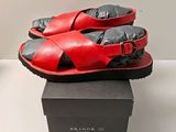 une paire de sandales rouges et noires posée sur une boîte noire