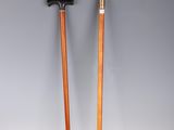 two wooden walking sticks with black handles on a white background