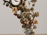a statue of a woman holding a clock with flowers on it