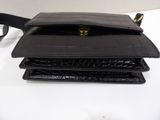 the black purse is sitting on a white table next to a pair of glasses
