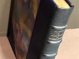 an old book sitting on top of a wooden table next to a wall