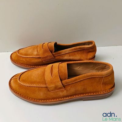 Mocassins pour homme de couleur beige posés sur une surface blanche, sur fond blanc