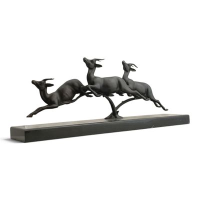 sculpture en bronze représentant trois cerfs en pleine course, posée sur un socle en bois