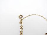 a close up of a gold chain bracelet with a key on a white surface