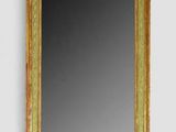 un miroir à cadre doré accroché à un mur blanc, à côté d'un autre mur blanc
