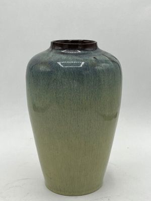 a green vase with a black lid on a white surface