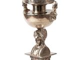 a silver cup on a pedestal with a statue on it