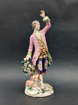 an antique figurine of a man with flowers and a dog
