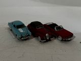 three toy cars sitting next to each other on a white surface