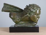 sculpture of a winged head on a marble base on a wooden table