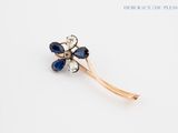 an image of a flower brooch with blue and white stones