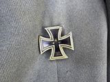 an iron cross pin with a black and gold cross on it ' s lapel