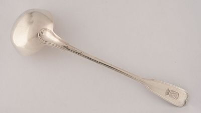 une cuillère ancienne en argent dont le manche repose sur une surface blanche