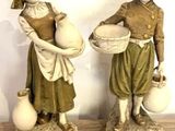 deux figurines représentant une femme et un homme tenant des cruches d'eau