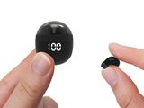deux mains tenant un petit objet noir sur lequel figure une horloge numérique