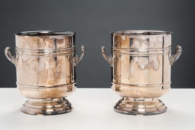 deux vases en argent posés sur une table, sur fond noir