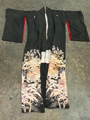 un gros plan d'un kimono noir et rouge posé sur un sol en béton