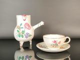 a tea pot and cup sitting on a table next to each other