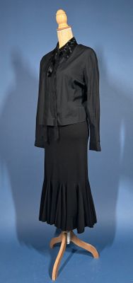 a black dress and jacket on a mannequin stand