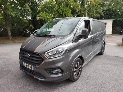La camionnette grise est garée sur un parking, avec des arbres en arrière-plan.