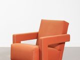 une chaise orange posée sur un sol en béton