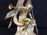 bronze statue of a woman sitting on a rock holding a trumpet