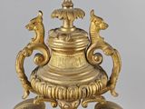 a gold vase with a bird on top of it