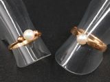 une paire de bagues ornées de perles, posées sur une surface noire