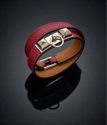 un gros plan d'un bracelet en cuir rouge posé sur une surface noire