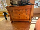 a dresser in the corner of a room with a lamp on top of it