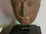 une statue représentant une tête posée sur un socle en bois