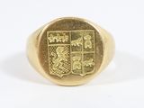 a close up of a gold signet ring with a coat of arms on it