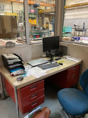 un bureau sur lequel se trouve un ordinateur, avec une chaise bleue devant