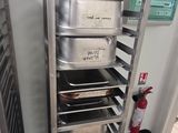 several trays of food sit on a metal rack in a kitchen