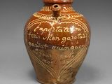 un vieux vase marron, orné d'une inscription, posé sur une table