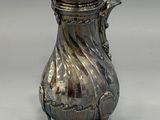 an antique silver coffee pot with a lid on a stand