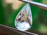 un gros diamant transparent tenu par une paire de pinces