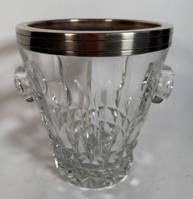 a glass ice bucket with a metal handle on a table