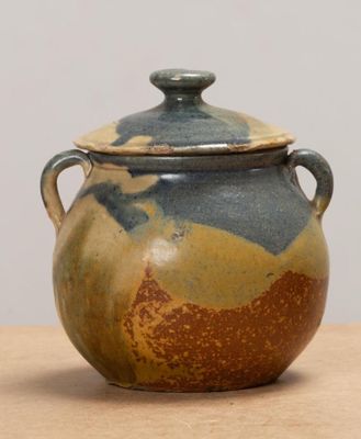 un vase marron et bleu avec un couvercle, posé sur une table