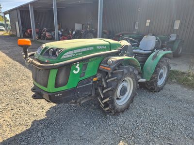 un tracteur vert garé devant un bâtiment