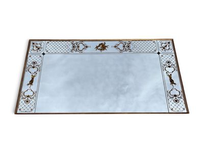 un grand miroir rectangulaire au motif ouvragé et à la bordure dorée
