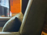 the back of a green chair with a pillow on it in a room