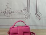 a pink purse on a wooden table with a white wall in the background