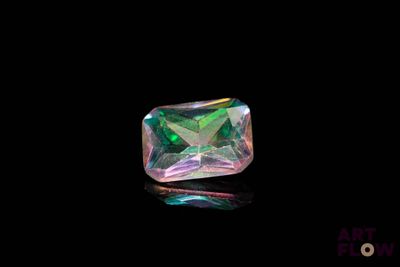 un gros plan d'un diamant vert et rose sur une surface noire