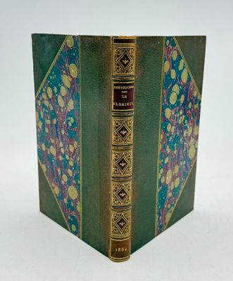 un vieux livre à la couverture verte, rehaussée de dorures sur fond blanc