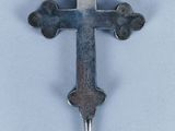 une croix argentée sur un fond blanc, dans laquelle est enfoncé un couteau