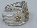 a close up of a silver bracelet with flowers on it