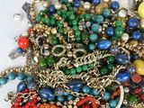 a pile of assorted beads and chains on a white surface