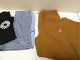 three pairs of men ' s nike pants and a t - shirt on a table